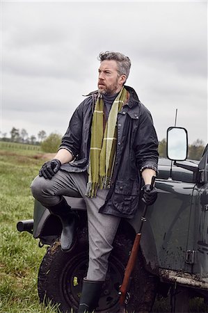 simsearch:649-07803230,k - Man hunting, leaning against off road vehicle in field with shot gun Photographie de stock - Premium Libres de Droits, Code: 614-08982667