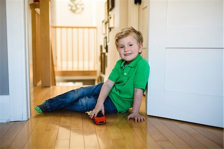 Portrait of boy with toy car sitting on floor Photographie de stock - Premium Libres de Droits, Code: 614-08982770