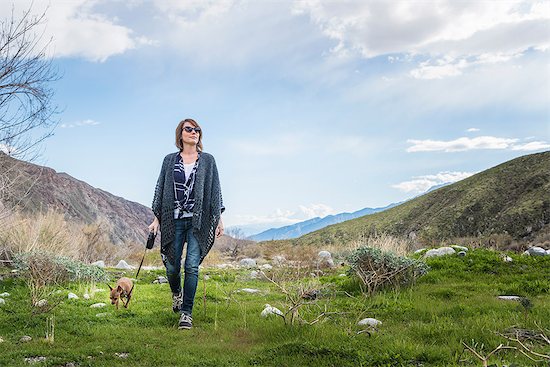 Mature woman walking dog in valley landscape Stock Photo - Premium Royalty-Free, Image code: 614-08982785