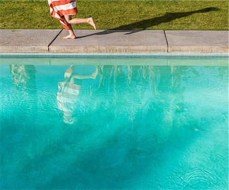 swimming pool with running water - Waist down view of boy wrapped in towel running on poolside Stock Photo - Premium Royalty-Free, Code: 614-08982791