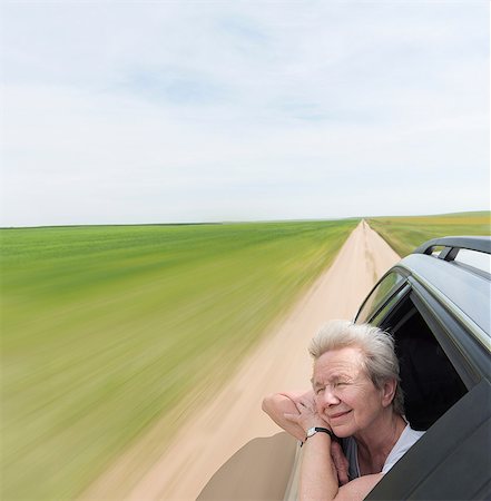 Senior woman leaning on car window enjoying wind in face Stock Photo - Premium Royalty-Free, Code: 614-08982830