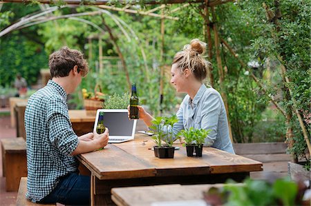 Couple with beer in garden using laptop Stock Photo - Premium Royalty-Free, Code: 614-08982877