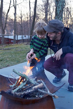 simsearch:649-08381271,k - Boy and father tending fire in patio fire pit Photographie de stock - Premium Libres de Droits, Code: 614-08982900