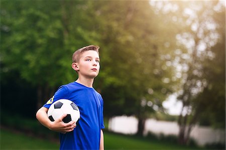 Boy holding soccer ball looking away Stock Photo - Premium Royalty-Free, Code: 614-08982996