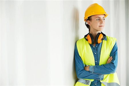 simsearch:649-06844887,k - Young woman, wearing hi vis vest and hard hat, leaning against wall, arms folded Stock Photo - Premium Royalty-Free, Code: 614-08983194