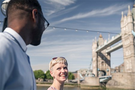 face to face icon - Young couple walking outdoors, smiling, Tower Bridge in background, London, England, UK Stock Photo - Premium Royalty-Free, Code: 614-08983253