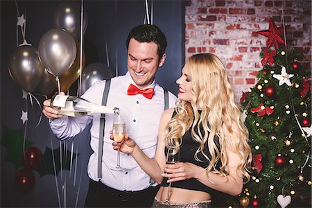 picture of champagne bottle and champagne flute - Man and woman at party, man pouring champagne into woman's glass Stock Photo - Premium Royalty-Free, Code: 614-08983326