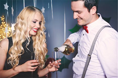 picture of champagne bottle and champagne flute - Man and woman at party, man pouring champagne into woman's glass Stock Photo - Premium Royalty-Free, Code: 614-08983327