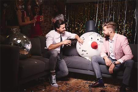 party de noël - Two men sitting on sofa at party, giant snowman head in-between them, laughing Photographie de stock - Premium Libres de Droits, Code: 614-08983354