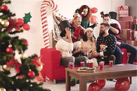 Young adult friends trying on party hats at christmas party Stock Photo - Premium Royalty-Free, Code: 614-08983437