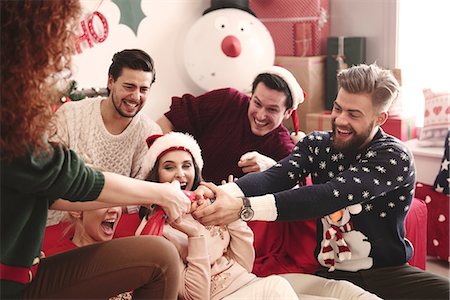 simsearch:614-08983460,k - Young adult friends pulling christmas crackers on sofa at christmas party Foto de stock - Royalty Free Premium, Número: 614-08983457