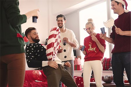 Young man balancing giant lollipop on his stomach at christmas party Stock Photo - Premium Royalty-Free, Code: 614-08983465