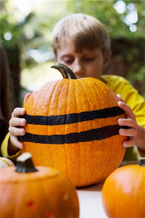 simsearch:614-08946611,k - Boy lifting large stripe painted pumpkin from garden table Stock Photo - Premium Royalty-Free, Code: 614-08983560