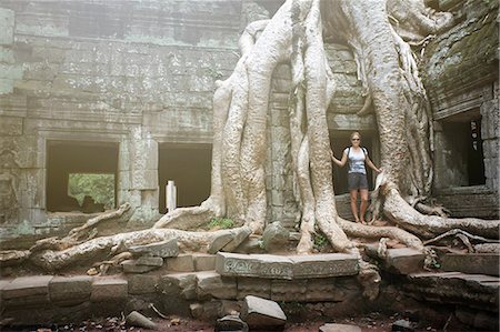 Portrait of young female tourist by tree roots at Ta Prohm temple, Angkor, Siem Reap, Cambodia Stock Photo - Premium Royalty-Free, Code: 614-08983573