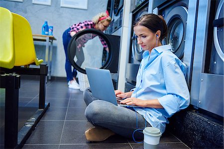 simsearch:649-08923947,k - Woman sitting on laundrette floor typing on laptop Stock Photo - Premium Royalty-Free, Code: 614-08983601