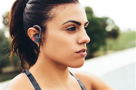 Portrait of young woman outdoors, wearing earphones close-up, South Point Park, Miami Beach, Florida, USA Stock Photo - Premium Royalty-Free, Code: 614-08983874