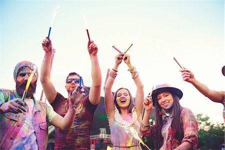Young adults covered in coloured chalk powder dancing with sparklers at festival Stock Photo - Premium Royalty-Free, Code: 614-08990467