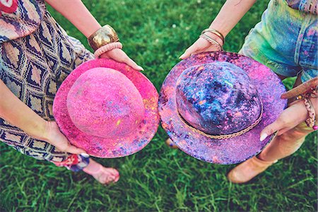 Waist down view of two young women holding felt hats covered in coloured chalk at festival Fotografie stock - Premium Royalty-Free, Codice: 614-08990470