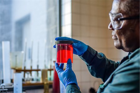 Lab technician looking at beaker of red biofuel in biofuel plant laboratory Photographie de stock - Premium Libres de Droits, Code: 614-08990516