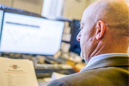 simsearch:614-08866451,k - Over shoulder view of businessman reading paperwork at office desk Fotografie stock - Premium Royalty-Free, Codice: 614-08990526