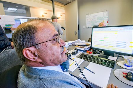 Over shoulder view of manager making telephone call at office desk Stock Photo - Premium Royalty-Free, Code: 614-08990531
