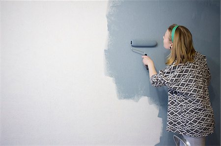 simsearch:614-08874958,k - Young woman on step ladder applying grey paint to interior wall at home Foto de stock - Sin royalties Premium, Código: 614-08990551