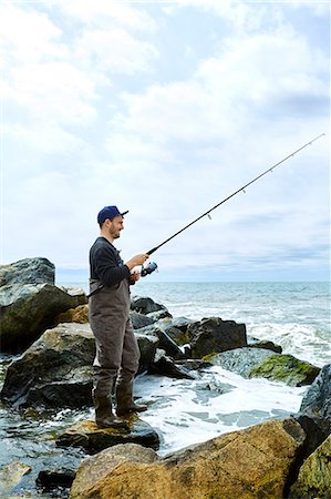 fishing waders - Young man standing on rock sea fishing Stock Photo - Premium Royalty-Free, Code: 614-08990744