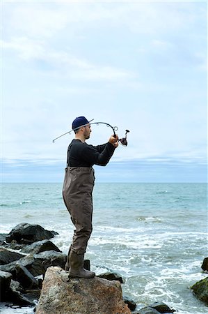 Waist down rear view of young couple in sea fishing waders on beach stock  photo