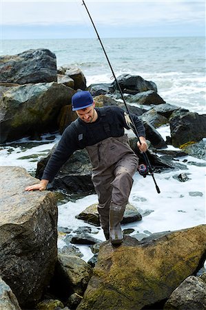 simsearch:614-08990745,k - Young male sea fisher clambering up beach rocks Photographie de stock - Premium Libres de Droits, Code: 614-08990743
