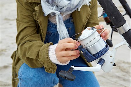 Mid section of female sea fisher checking fishing reel on beach Foto de stock - Sin royalties Premium, Código: 614-08990774