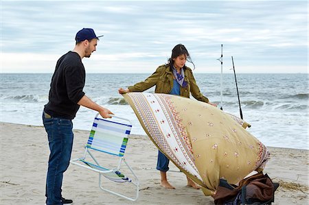 simsearch:614-08990745,k - Young sea fishing couple preparing beach chair and picnic blanket on beach Photographie de stock - Premium Libres de Droits, Code: 614-08990778