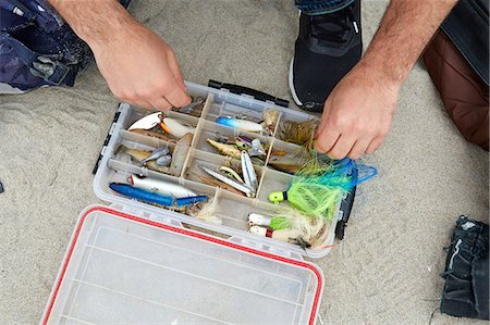 sportfishing - Male sea fisher hands selecting fishing hook on beach Stock Photo - Premium Royalty-Free, Code: 614-08990772