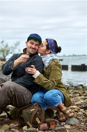 Young woman kissing boyfriend on cheek on beach Stock Photo - Premium Royalty-Free, Code: 614-08990789