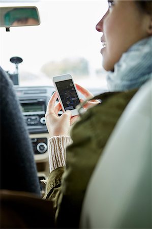 roadtrip gps - Young couple sitting in car, woman holding smartphone, rear view Stock Photo - Premium Royalty-Free, Code: 614-08990810