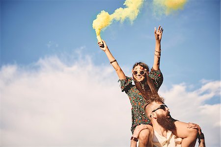Young boho woman holding yellow smoke flare on boyfriend's shoulders at festival Stock Photo - Premium Royalty-Free, Code: 614-08991271