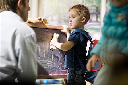 Boy cleaning blackboard with duster Stock Photo - Premium Royalty-Free, Code: 614-09017476