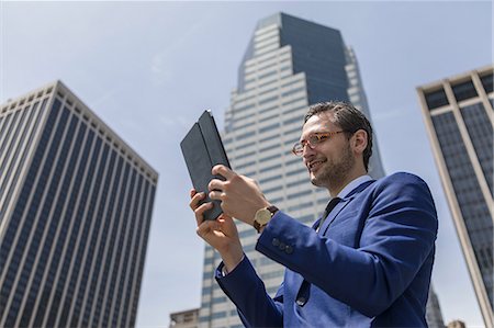 simsearch:614-08081363,k - Smiling young businessman looking at digital tablet by New York skyscrapers, USA Photographie de stock - Premium Libres de Droits, Code: 614-09017489
