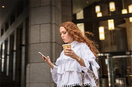 simsearch:649-08824700,k - Young businesswoman with takeaway coffee looking at smartphone on sidewalk, New York, USA Foto de stock - Royalty Free Premium, Número: 614-09017494