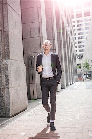 simsearch:614-09017557,k - Cool businessman with takeaway coffee strolling along sidewalk, New York, USA Fotografie stock - Premium Royalty-Free, Codice: 614-09017491