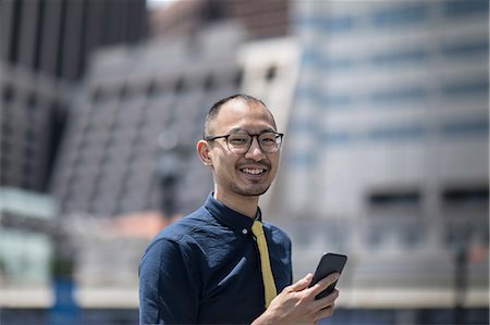 simsearch:614-09017513,k - Portrait of smiling businessman with smartphone outside office building, New York, USA Stock Photo - Premium Royalty-Free, Code: 614-09017507
