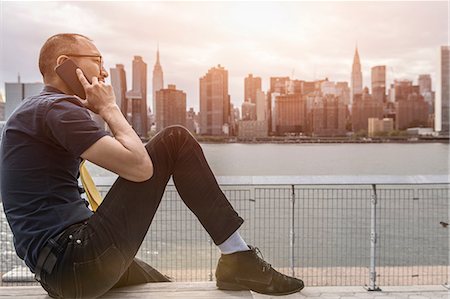 simsearch:614-09017513,k - Businessman sitting on waterfront making smartphone call, New York, USA Stock Photo - Premium Royalty-Free, Code: 614-09017564