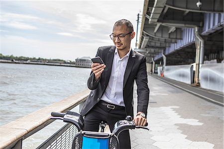 simsearch:614-08827243,k - Businessman cyclist looking at smartphone on waterfront, New York, USA Stock Photo - Premium Royalty-Free, Code: 614-09017560