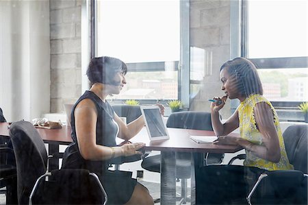 solución - Two women working together in meeting room, brainstorming, using digital tablet Foto de stock - Sin royalties Premium, Código: 614-09017717