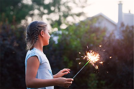 Girl holding sparkler in garden at dusk on independence day, USA Stock Photo - Premium Royalty-Free, Code: 614-09026499