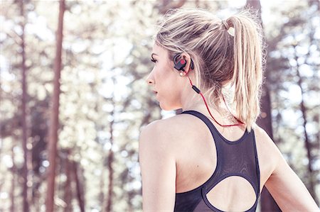 Young woman in rural setting, wearing sports clothing and earphones, rear view Stock Photo - Premium Royalty-Free, Code: 614-09026705
