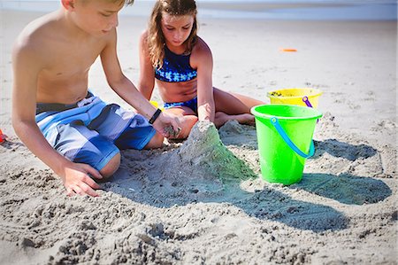 Siblings playing with sand on beach Stock Photo - Premium Royalty-Free, Code: 614-09026971