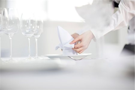 Waitress laying table in restaurant, mid section Stock Photo - Premium Royalty-Free, Code: 614-09027143