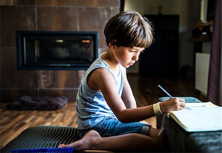 education and kids - Boy kneeling on floor drawing in workbook Stock Photo - Premium Royalty-Free, Code: 614-09038548