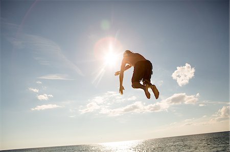 simsearch:614-09038554,k - Young man jumping into water, mid air, rear view Foto de stock - Sin royalties Premium, Código: 614-09038591