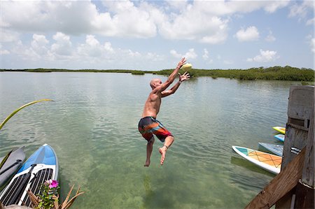 Mature man jumping into water, mid air Stock Photo - Premium Royalty-Free, Code: 614-09038606